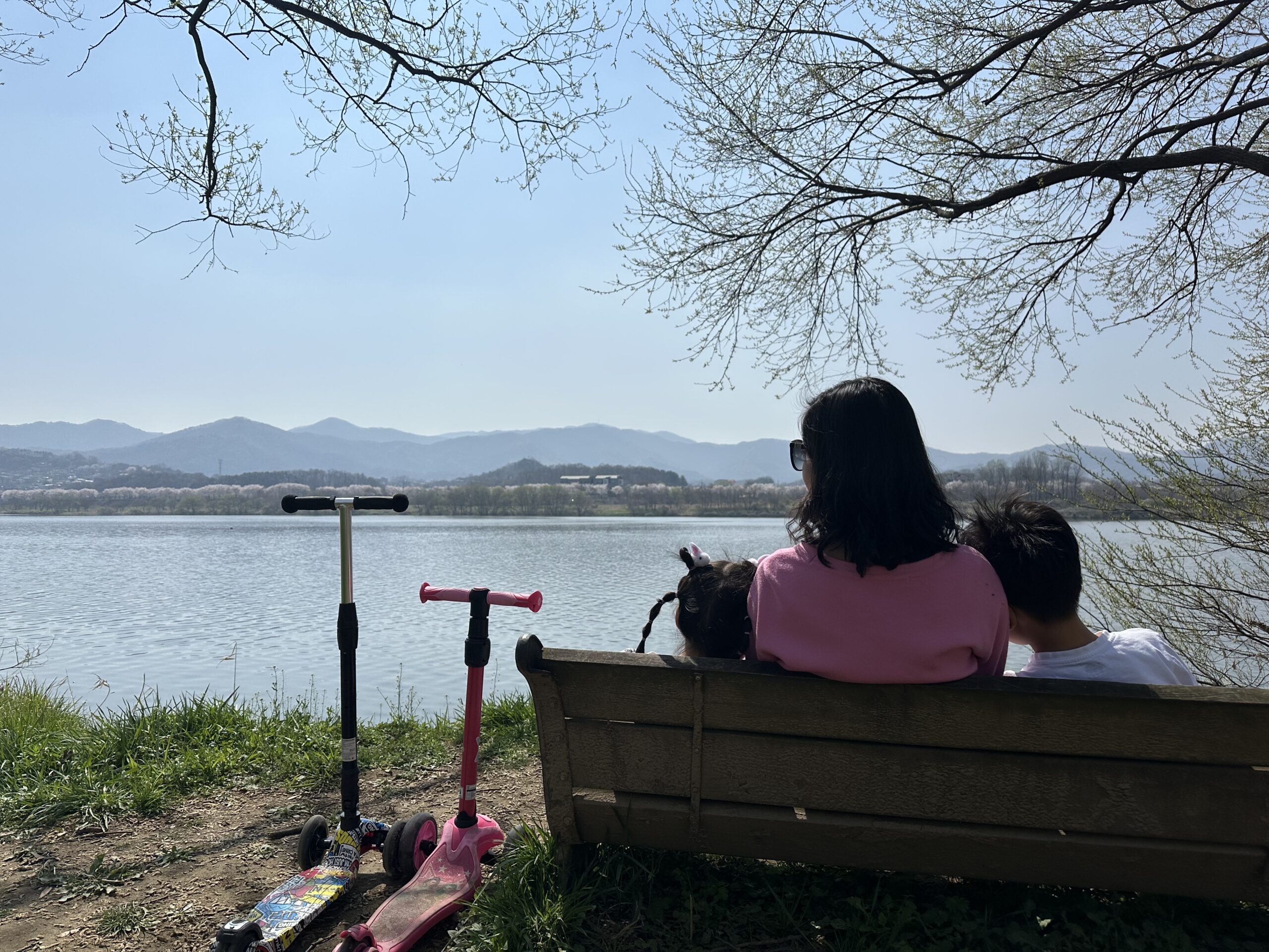 벤치에 앉아 강을 바라보는 엄마와 아이들