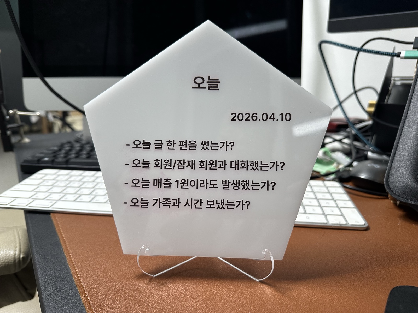 책상 위 오각형 아크릴 패널, 오늘의 네 가지 질문이 새겨져 있다